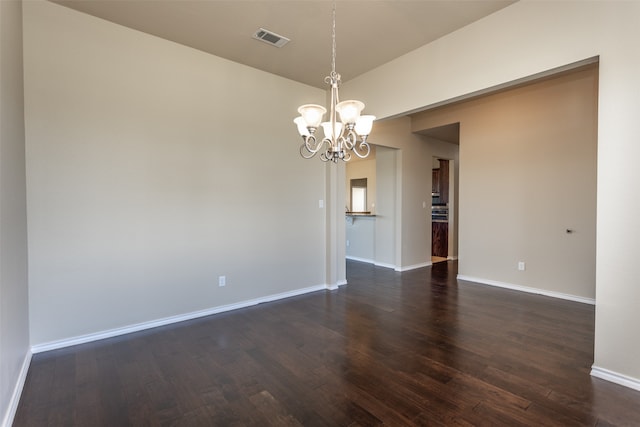 empty room with dark wood-type flooring and a chandelier