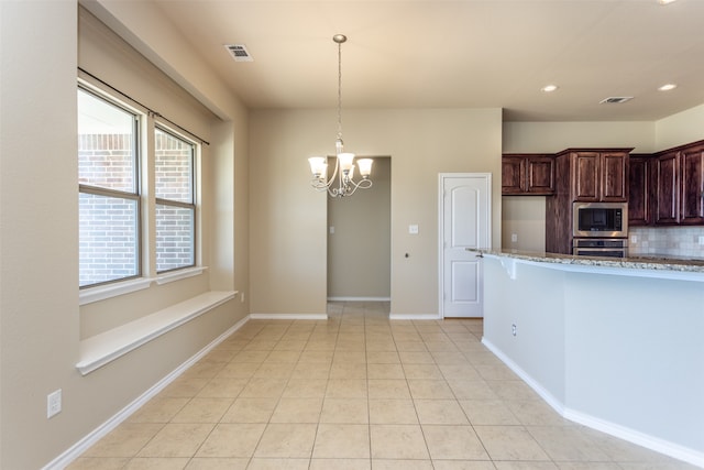 kitchen with built in microwave, stainless steel oven, an inviting chandelier, pendant lighting, and decorative backsplash