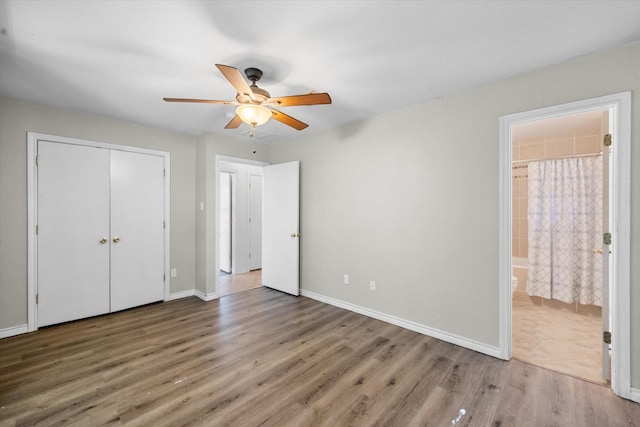 unfurnished bedroom with ceiling fan, hardwood / wood-style floors, a closet, and ensuite bath