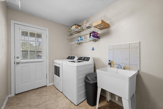 laundry area featuring separate washer and dryer, light tile patterned floors, and sink