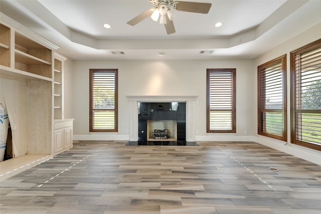 unfurnished living room featuring hardwood / wood-style flooring, ceiling fan, and a tray ceiling