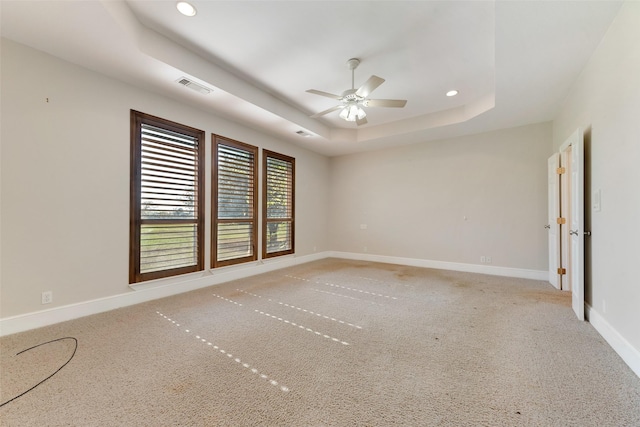 carpeted spare room featuring ceiling fan and a raised ceiling