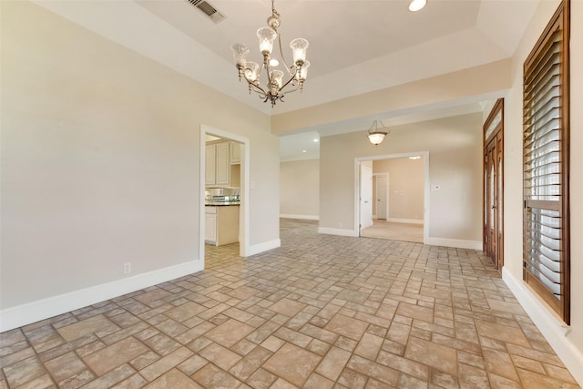 empty room featuring an inviting chandelier and a tray ceiling