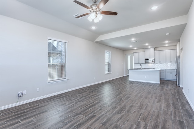 unfurnished living room with dark hardwood / wood-style floors, ceiling fan, and sink