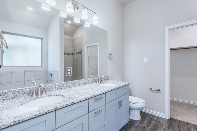 bathroom with hardwood / wood-style floors, vaulted ceiling, an enclosed shower, toilet, and vanity