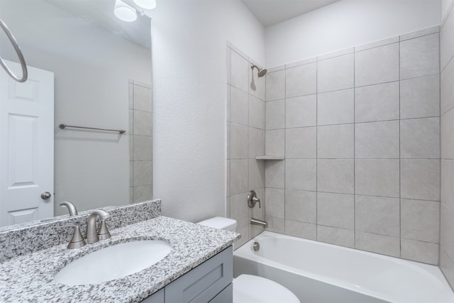 full bathroom featuring vanity, tiled shower / bath combo, and toilet