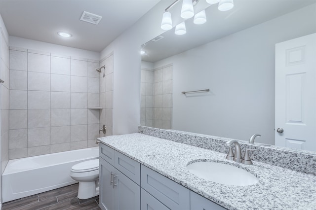 full bathroom featuring hardwood / wood-style flooring, tiled shower / bath combo, toilet, and vanity