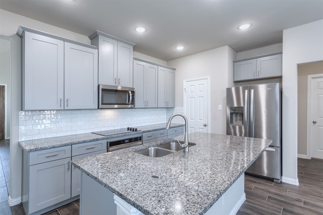 kitchen featuring a center island with sink, sink, appliances with stainless steel finishes, and dark wood-type flooring