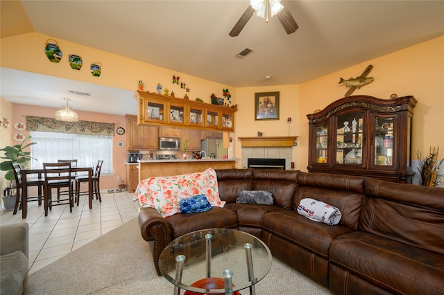 tiled living room featuring a tile fireplace, ceiling fan, and lofted ceiling