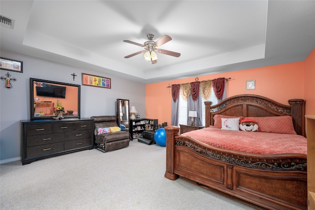 bedroom with a tray ceiling, ceiling fan, and carpet