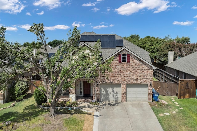 view of front of property featuring a garage, a front yard, and solar panels