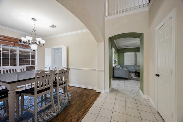 dining room with ornamental molding, light tile patterned floors, and an inviting chandelier