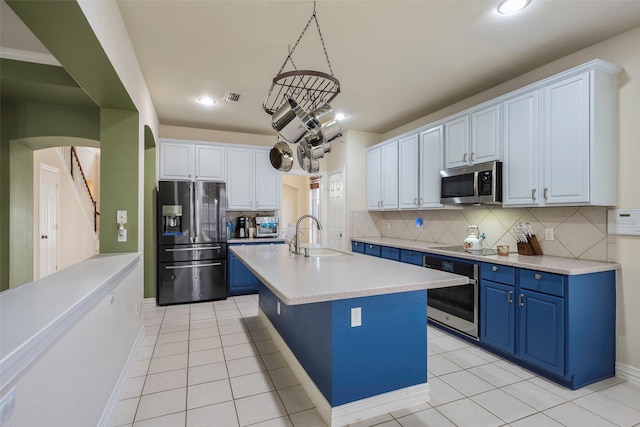 kitchen featuring a kitchen island with sink, white cabinets, sink, decorative light fixtures, and stainless steel appliances