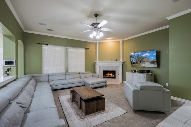 carpeted living room with ceiling fan, ornamental molding, and a tile fireplace