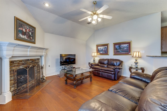 living room with a stone fireplace, ceiling fan, hardwood / wood-style floors, and lofted ceiling