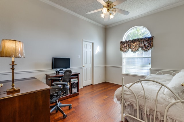 bedroom featuring hardwood / wood-style flooring, ceiling fan, ornamental molding, and a textured ceiling