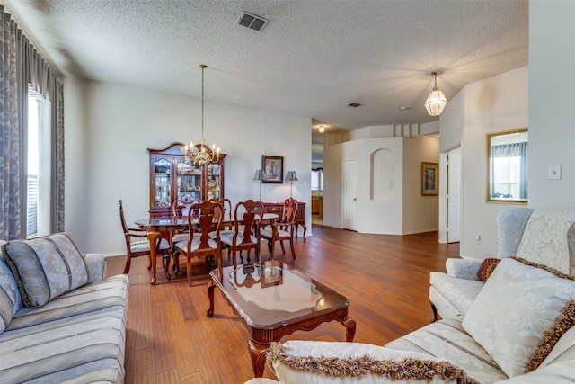 living room featuring a notable chandelier, wood-type flooring, and a textured ceiling