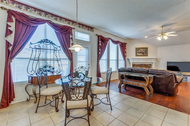 dining area with ceiling fan, light wood-type flooring, a textured ceiling, and vaulted ceiling