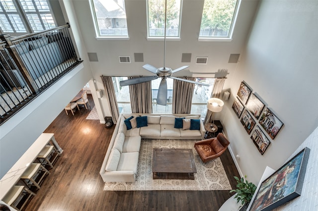 living room with hardwood / wood-style floors, a towering ceiling, and a healthy amount of sunlight