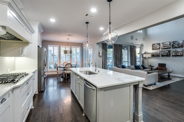 kitchen with sink, stainless steel appliances, decorative light fixtures, a center island with sink, and white cabinets