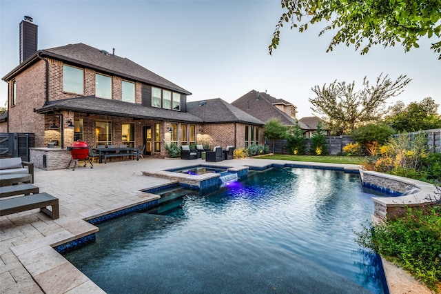 view of pool with exterior kitchen, an outdoor living space, pool water feature, an in ground hot tub, and a patio