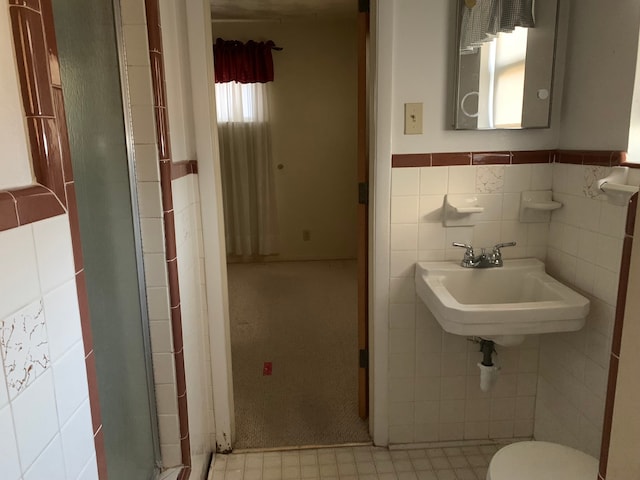 bathroom with sink, tile walls, and toilet