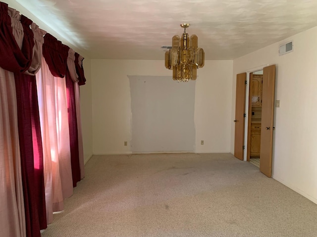 carpeted spare room featuring a chandelier