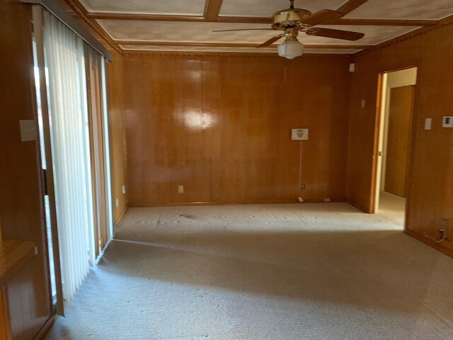 spare room with ceiling fan, light colored carpet, and wooden walls