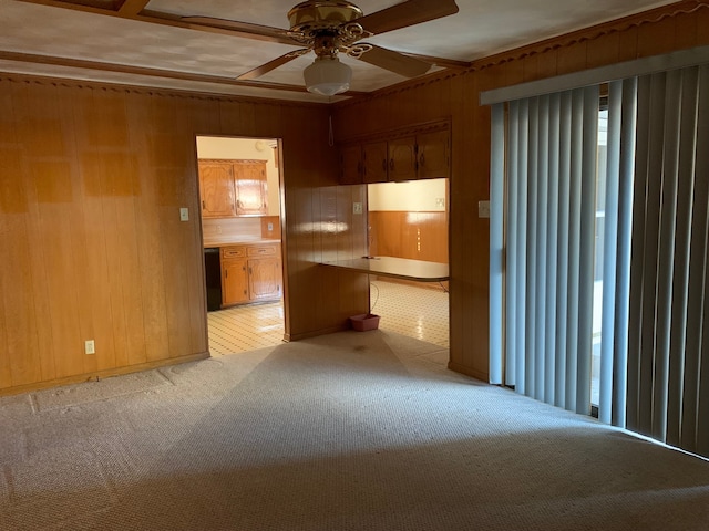 carpeted spare room featuring ceiling fan and wood walls