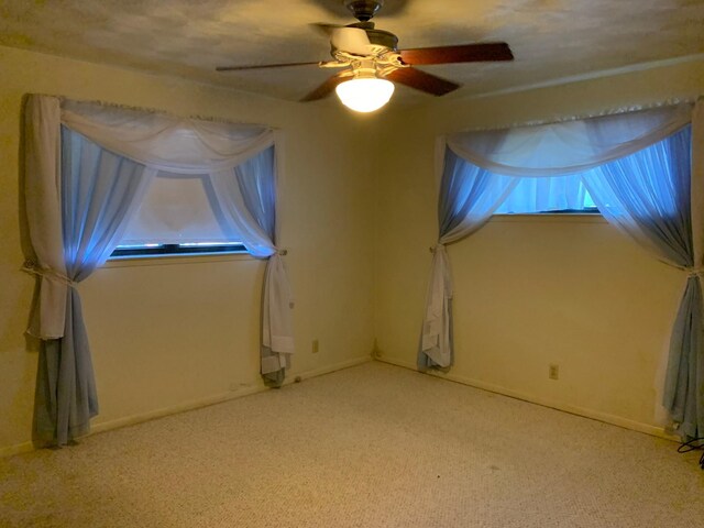 empty room featuring ceiling fan and light colored carpet