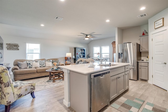 kitchen with stainless steel appliances, light hardwood / wood-style flooring, a center island with sink, and sink