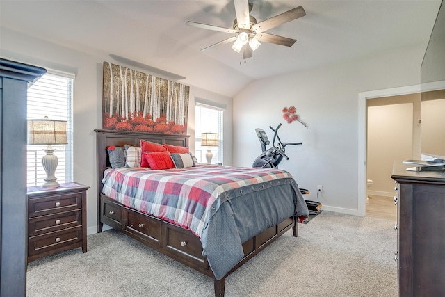 carpeted bedroom with ensuite bathroom, multiple windows, lofted ceiling, and ceiling fan