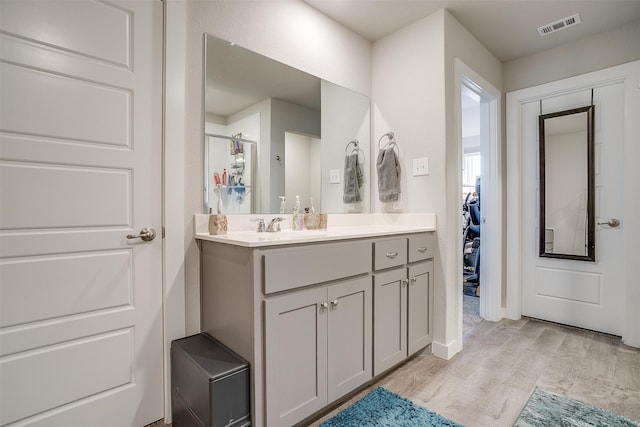 bathroom with vanity, a shower with shower door, and wood-type flooring