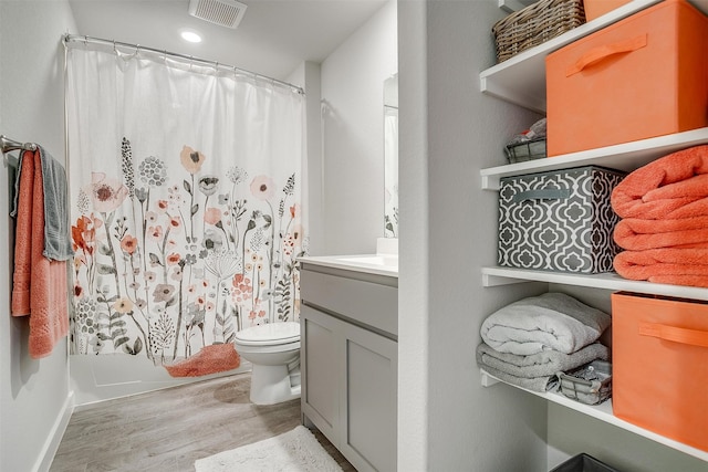 full bathroom featuring vanity, hardwood / wood-style flooring, toilet, and shower / bathtub combination with curtain