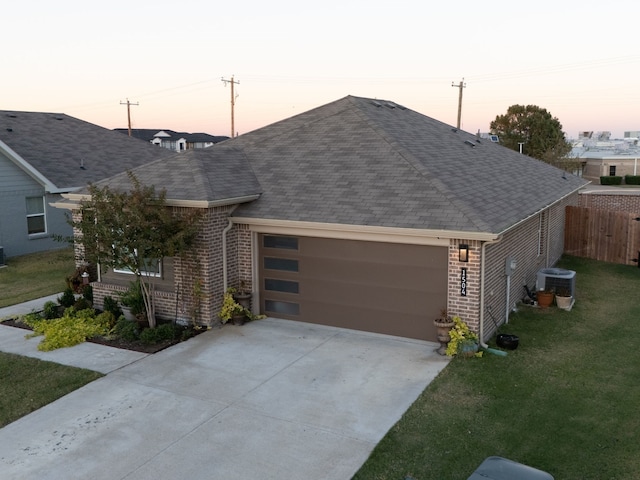 single story home featuring a yard, a garage, and central air condition unit