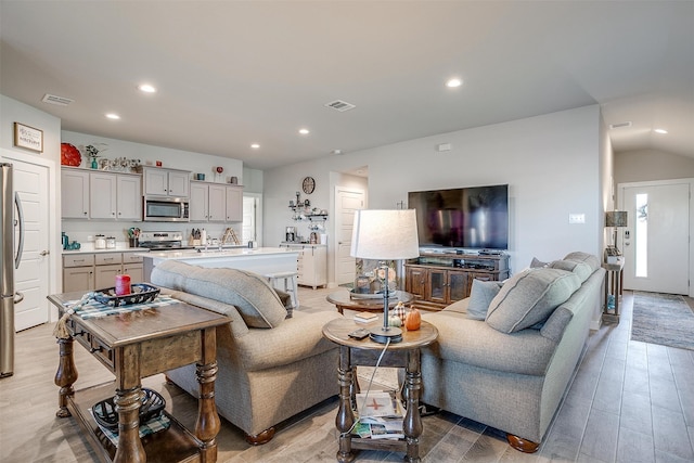 living room with vaulted ceiling and light wood-type flooring