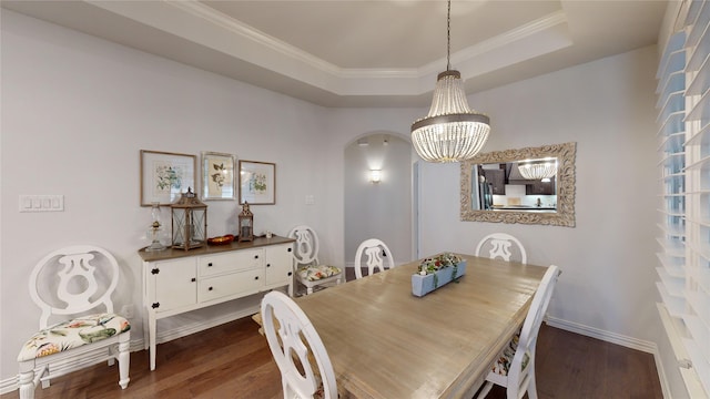 dining area with ornamental molding, dark hardwood / wood-style flooring, a tray ceiling, and a notable chandelier