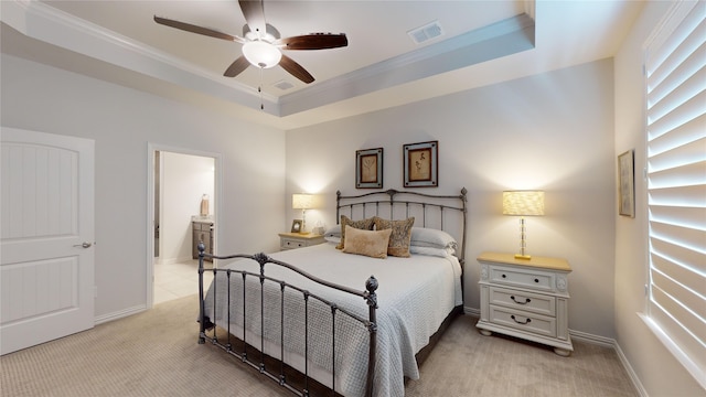 bedroom with ceiling fan, crown molding, connected bathroom, and a tray ceiling