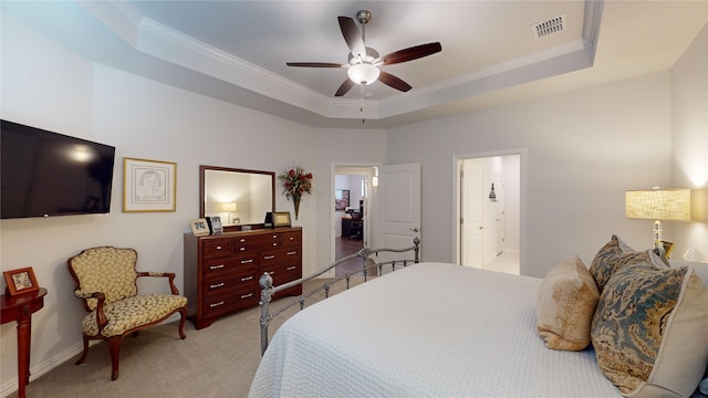 bedroom featuring connected bathroom, ceiling fan, light colored carpet, a tray ceiling, and ornamental molding