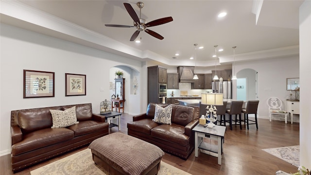 living room with dark hardwood / wood-style flooring, ceiling fan, and crown molding