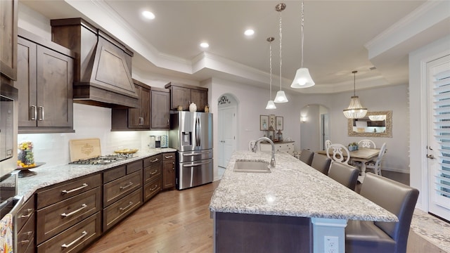 kitchen featuring a breakfast bar, a kitchen island with sink, sink, and appliances with stainless steel finishes