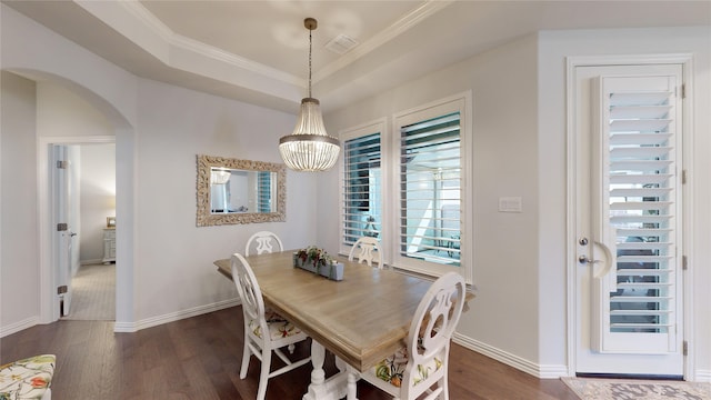 dining room with a tray ceiling, dark hardwood / wood-style flooring, an inviting chandelier, and ornamental molding