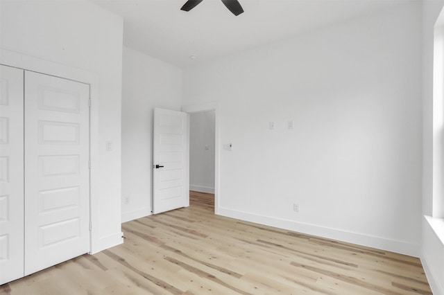 unfurnished bedroom with ceiling fan, light wood-type flooring, and a closet