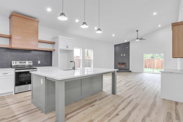 kitchen featuring electric range, white cabinetry, decorative light fixtures, and a fireplace