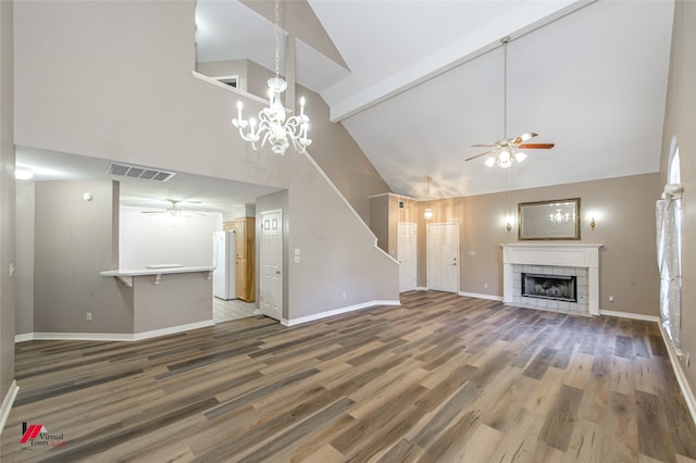 unfurnished living room featuring hardwood / wood-style floors, high vaulted ceiling, an inviting chandelier, beam ceiling, and a tiled fireplace