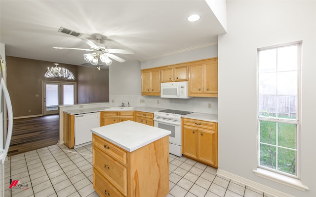 kitchen with light tile patterned flooring, white appliances, ceiling fan with notable chandelier, sink, and a kitchen island