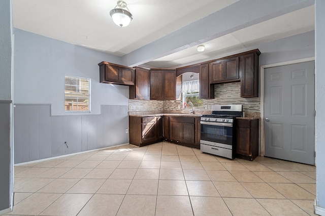 kitchen featuring dark brown cabinets, wood walls, stainless steel range, and tasteful backsplash