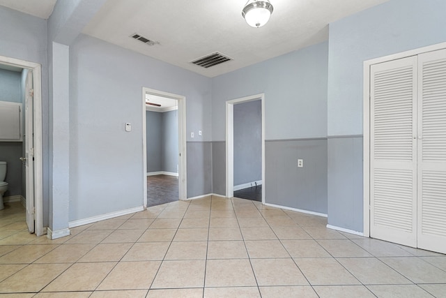 unfurnished bedroom with connected bathroom, a closet, and light tile patterned floors