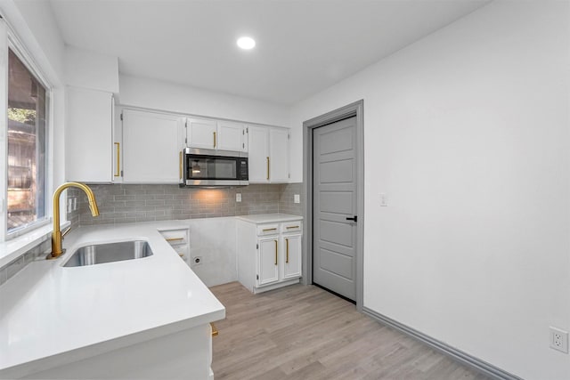 kitchen featuring sink, backsplash, white cabinetry, and plenty of natural light