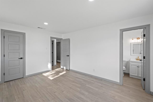 unfurnished bedroom featuring light hardwood / wood-style flooring and connected bathroom